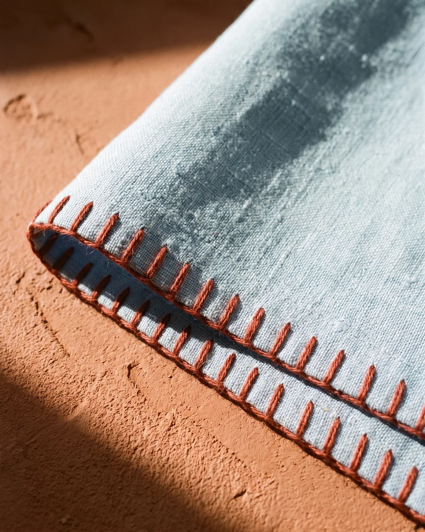 Kaftan Porto Cervo en azul cielo con bordado rojo, en macro, la textura del material