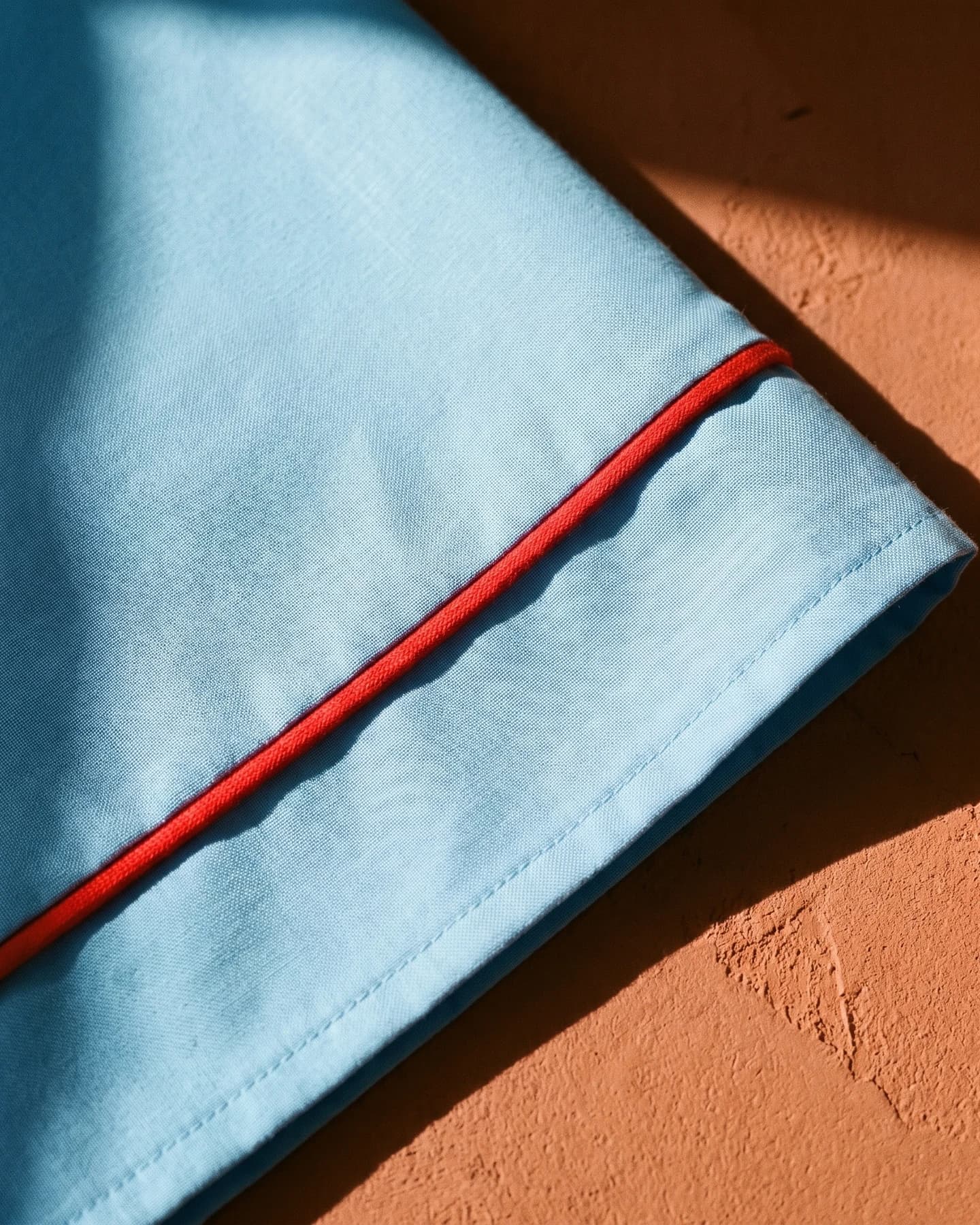 Pantalón Do Santos en azul con bordado rojo, en macro, la textura del material