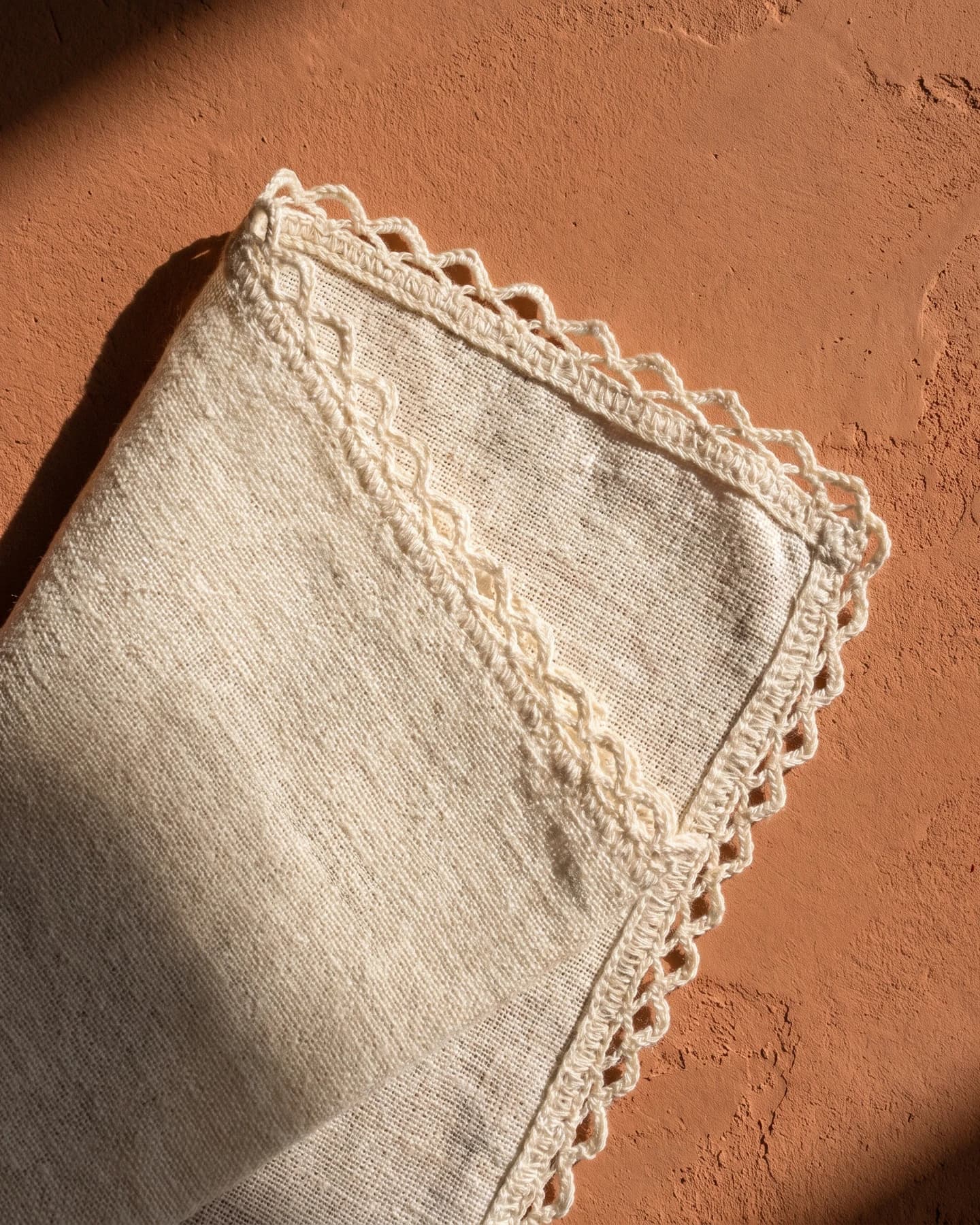 Poncho Cannes en blanco con bordado verde oliva, en macro, la textura del material